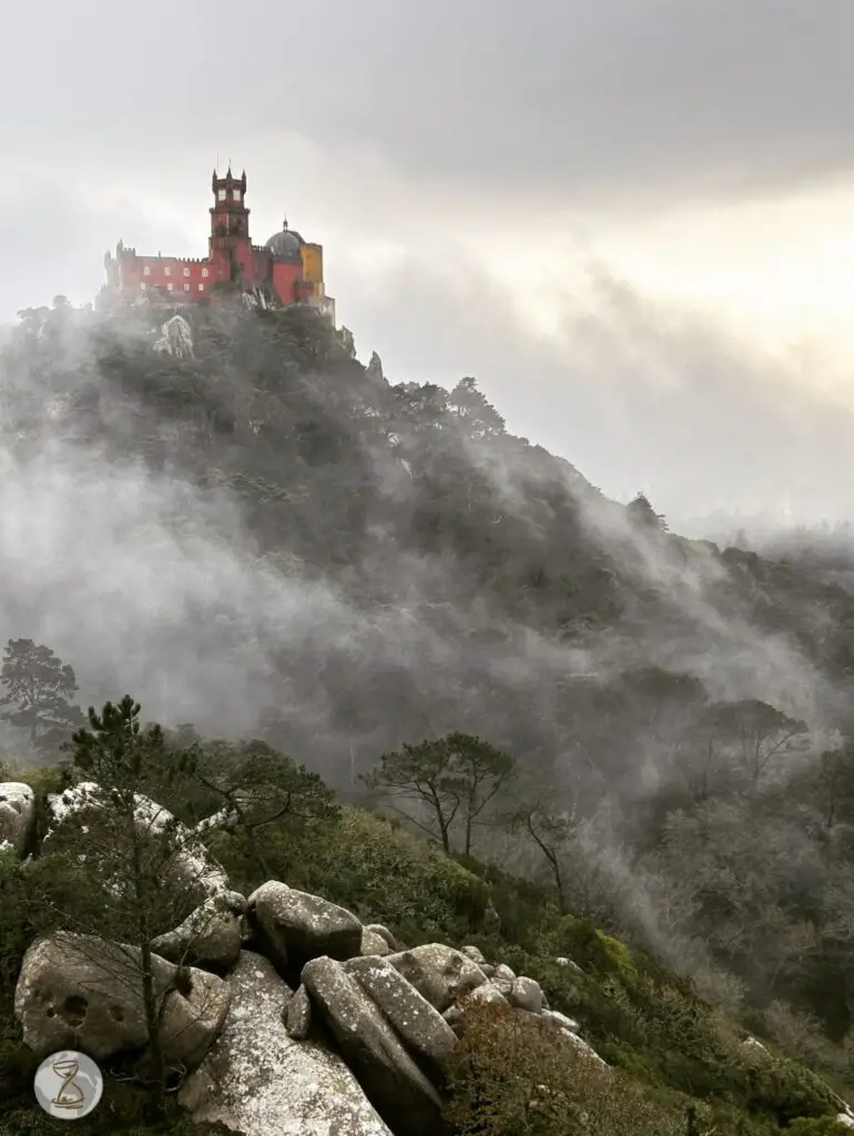 Pena palace rising through misty forest-covered mountains